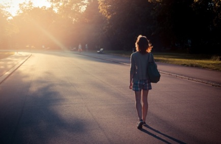 Woman walking into sunset in a park